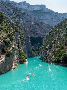Kayakers navigating turquoise waters between cliffs at Lake of Sainte-Croix, France.