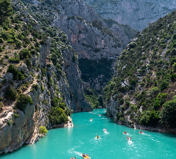 Kayakers navigating turquoise waters between cliffs at Lake of Sainte-Croix, France.