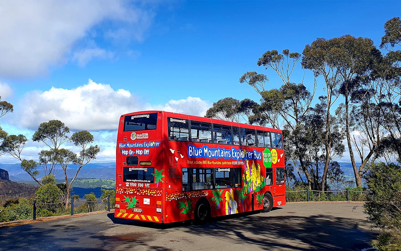 Red double-decker bus on Blue Mountains sightseeing tour with scenic view.