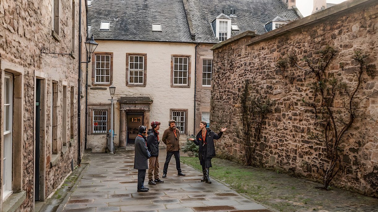 Tour group on the Royal Mile in Edinburgh with guide explaining historic site.