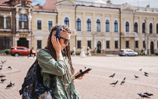 Self-guided audio tour participant in Amsterdam with headphones and tablet.