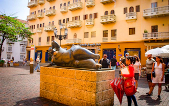 Botero sculpture in Cartagena's Walled Old City with tourists exploring the plaza.