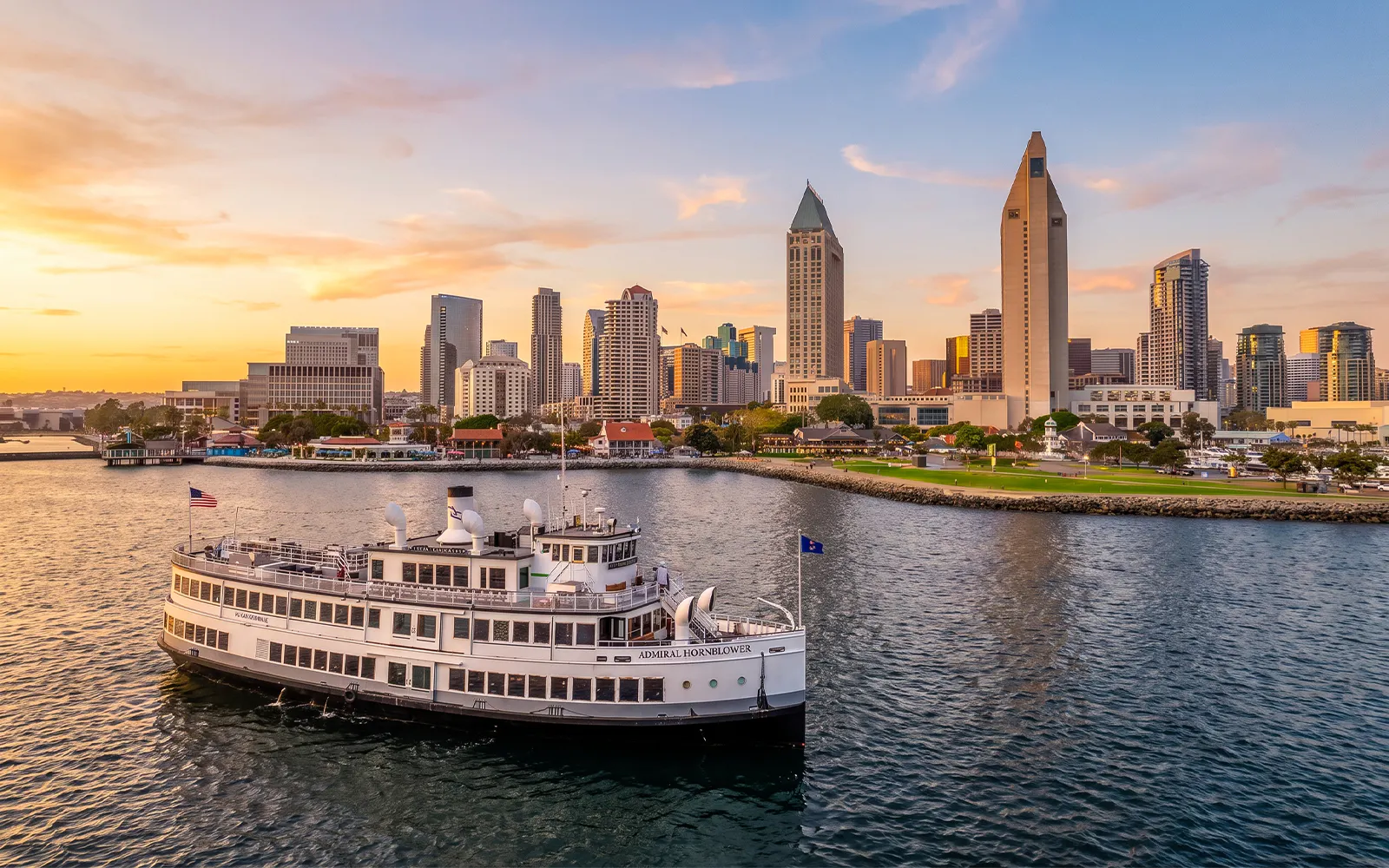 San Diego Premier Cruise sailing by city skyline at sunset.