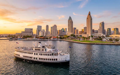 San Diego Premier Cruise sailing by city skyline at sunset.
