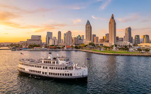 San Diego Premier Cruise sailing by city skyline at sunset.