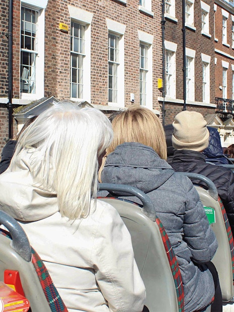 Passengers on open-top bus tour in Liverpool city.
