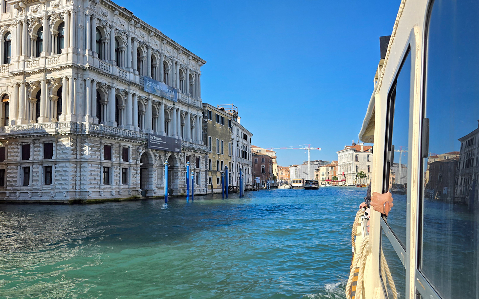 Vaporetto cruising through Venice's Grand Canal with historic buildings in view.