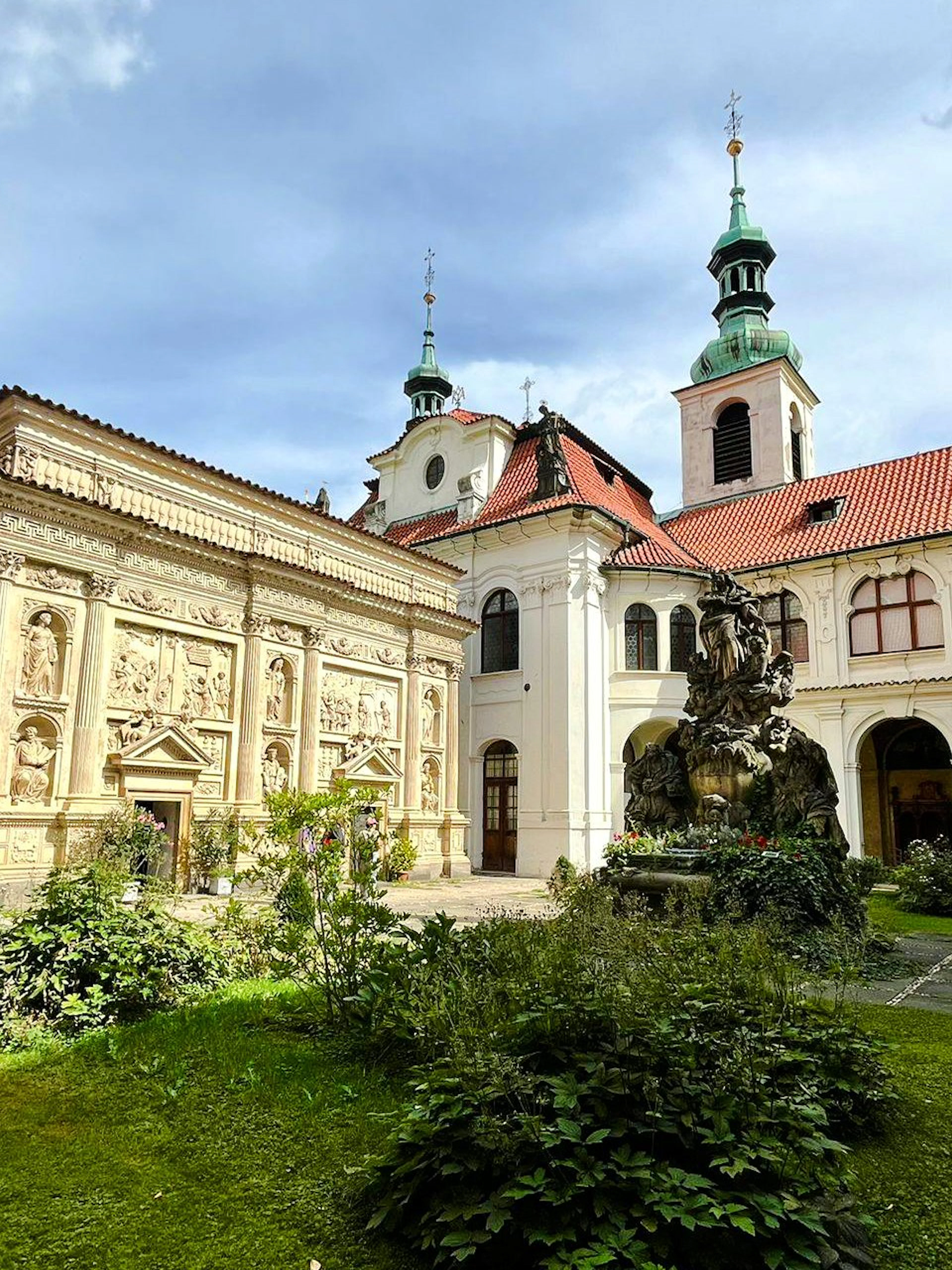 Inner courtyard of the Loreto complex in Prague with ornate architecture and a central fountain.