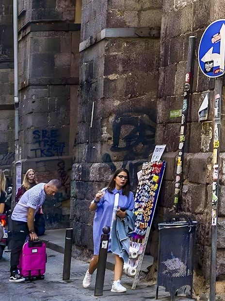 Exploring bustling historic alley in Naples with shops and tourists.