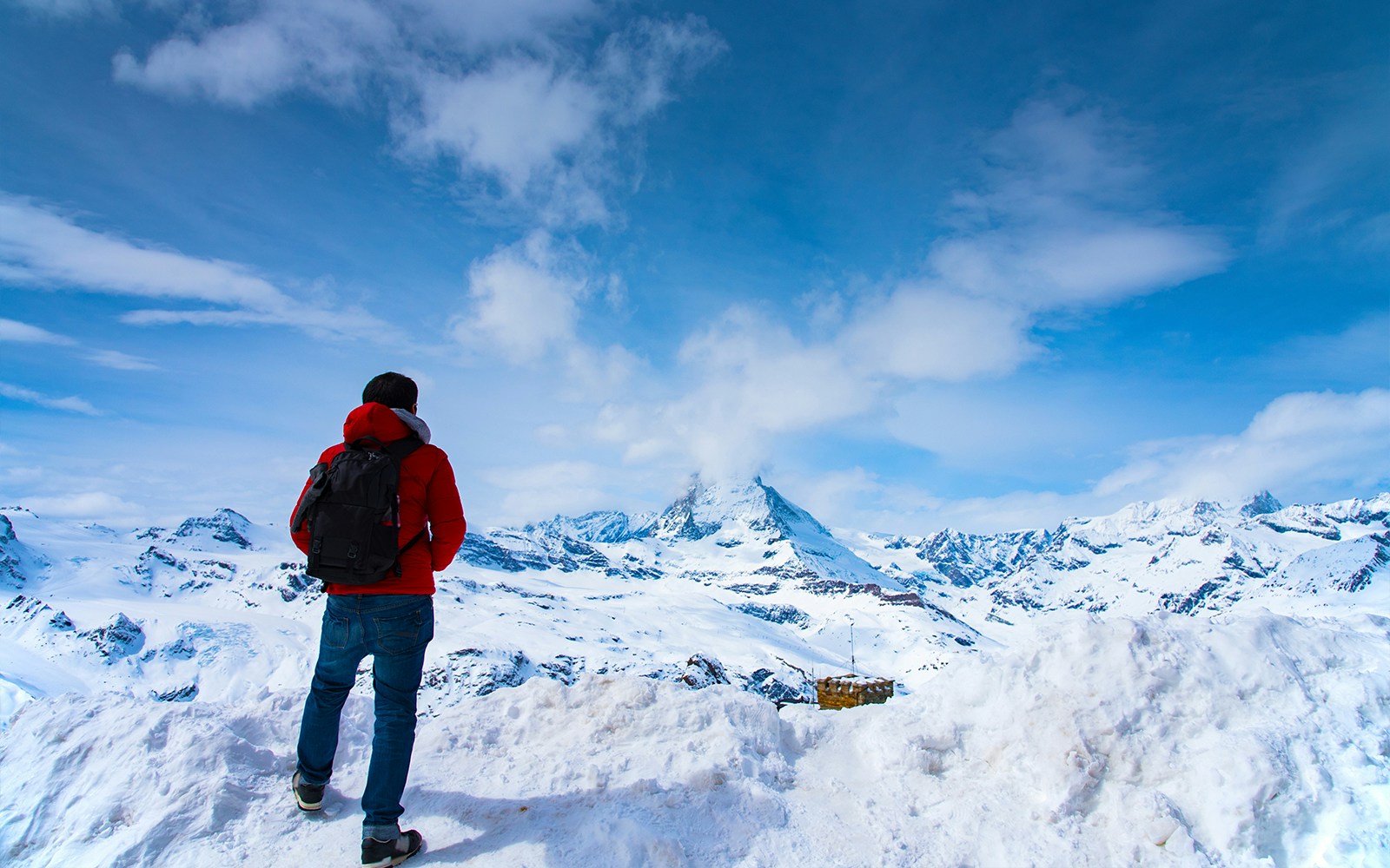 Man in red jacket viewing Matterhorn from Gornergrat, Zermatt, Switzerland.