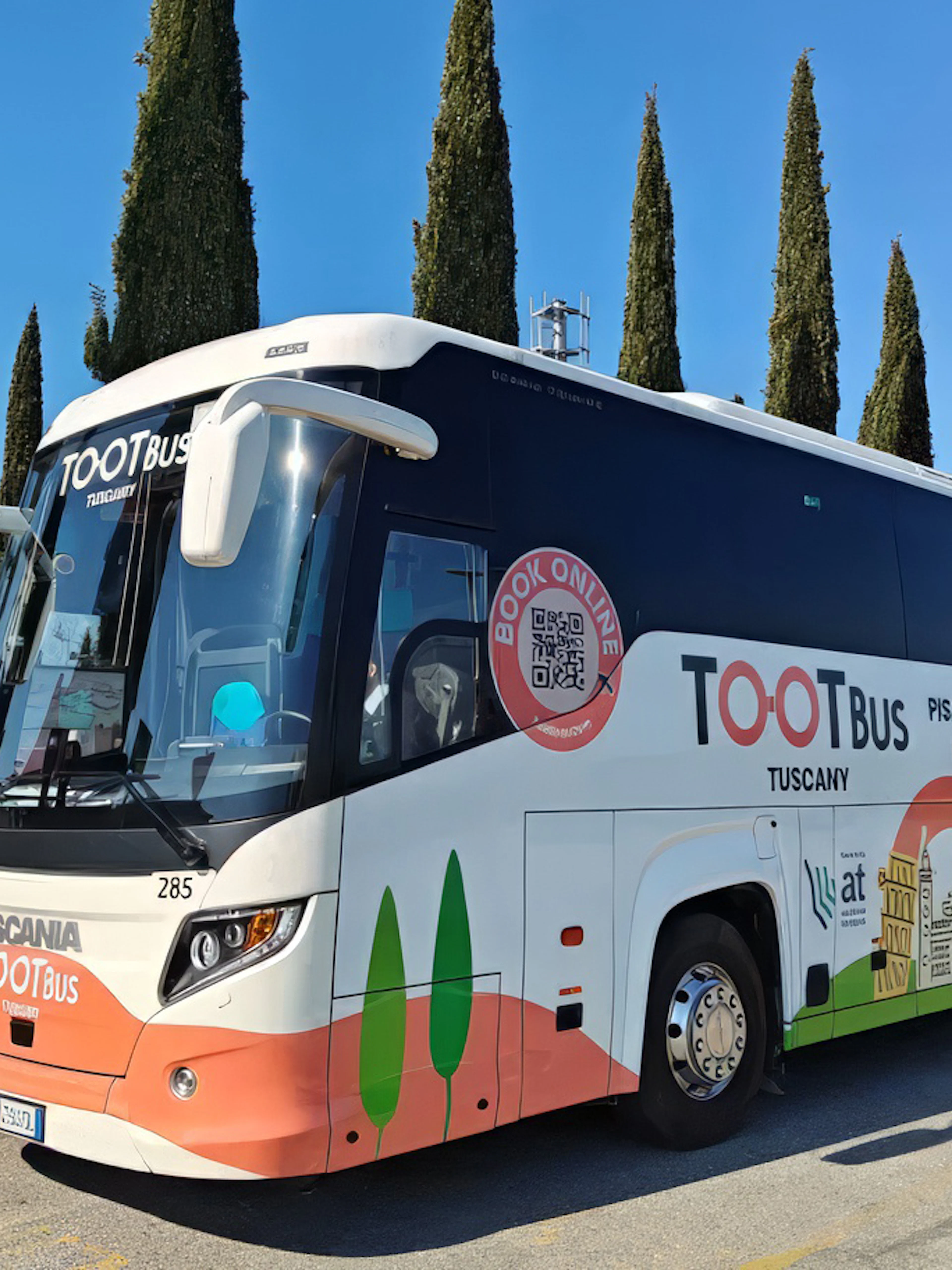 Tootbus Tuscany tour bus parked near cypress trees in Tuscany, Italy.