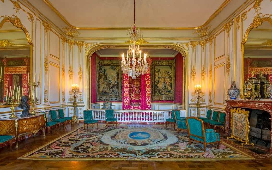Chambord Castle room interior with ornate tapestries, chandelier, and antique furniture.