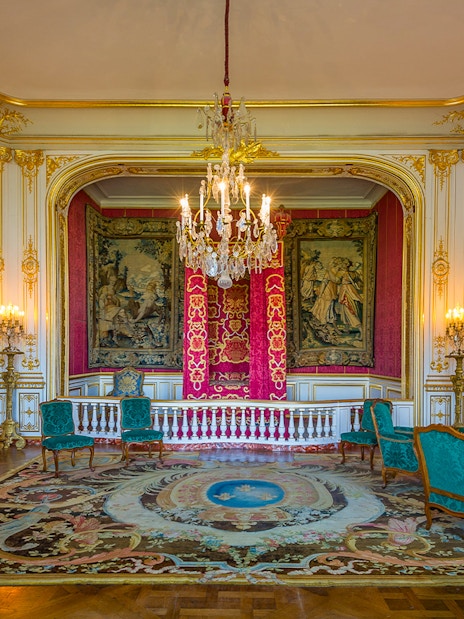 Chambord Castle room interior with ornate tapestries, chandelier, and antique furniture.
