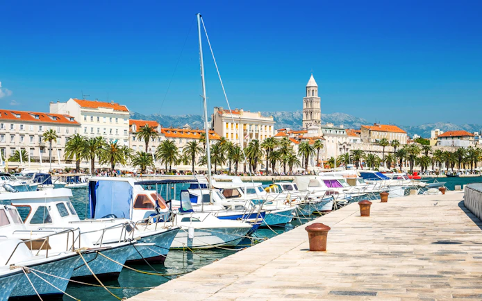 Boats docked along the Riva promenade with Diocletian's Palace in Split, Croatia.