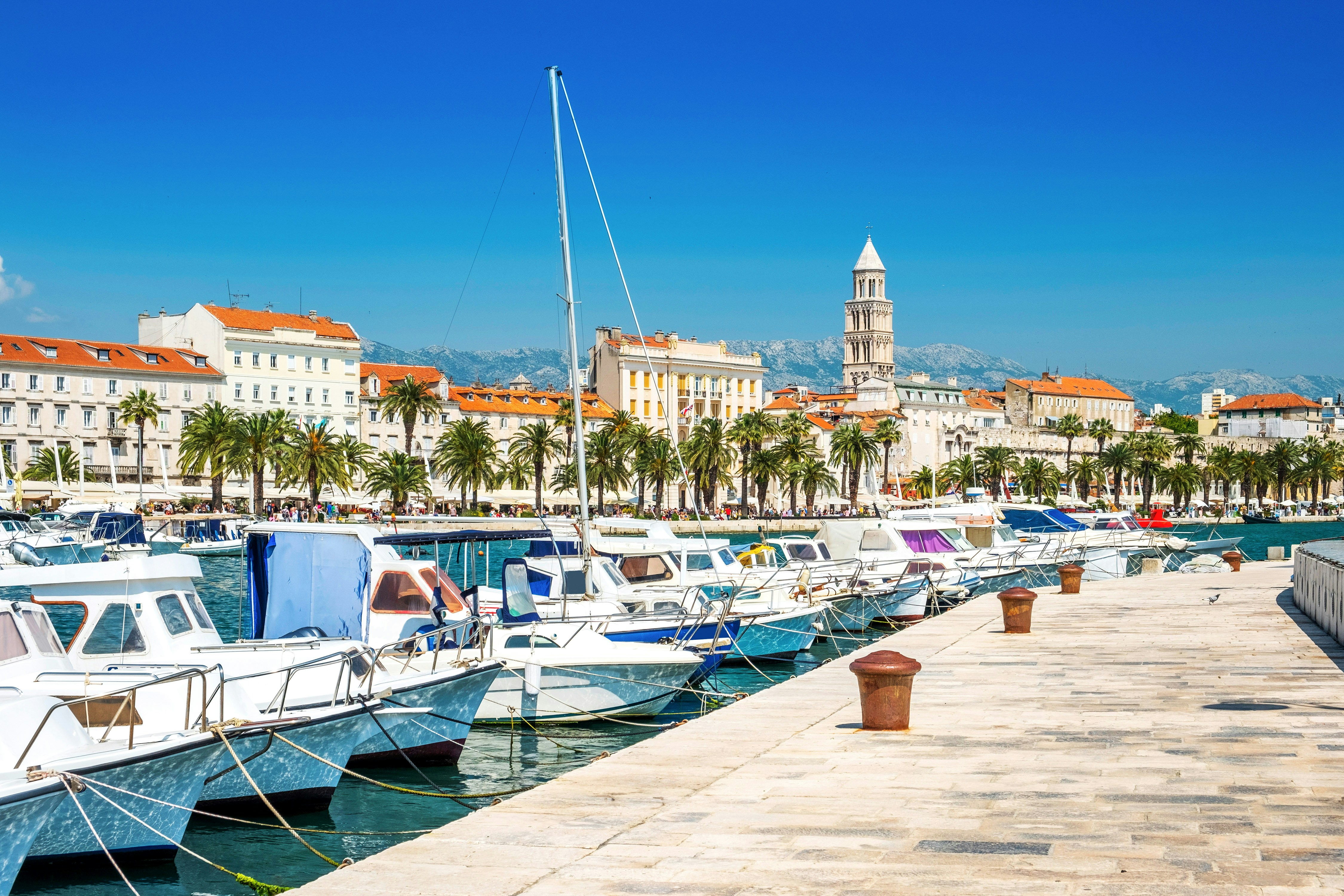 Boats docked along the Riva promenade with Diocletian's Palace in Split, Croatia.