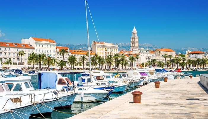 Boats docked along the Riva promenade with Diocletian's Palace in Split, Croatia.