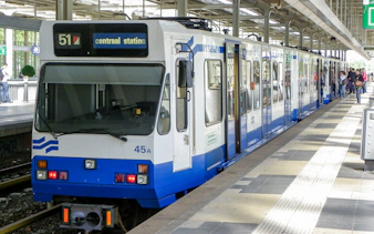 Tram at Amsterdam Centraal Station platform with passengers boarding.