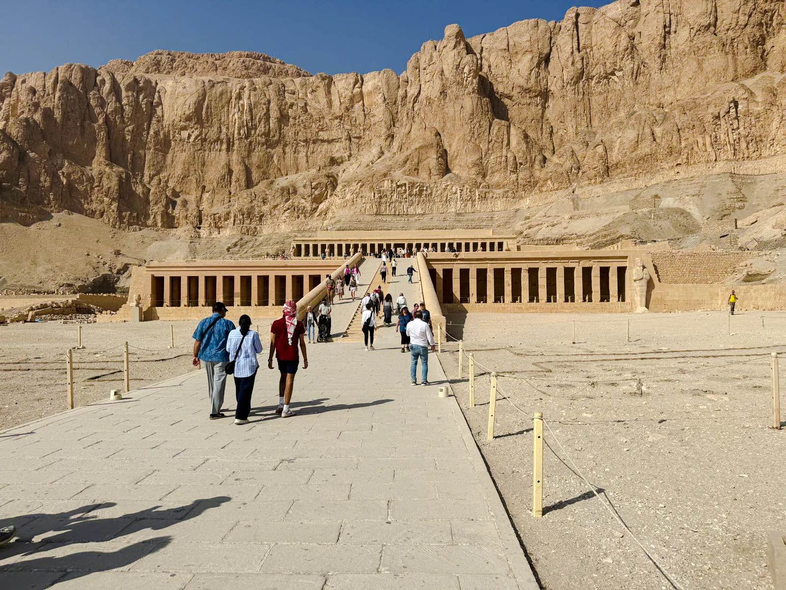 Hatshepsut Temple in Luxor with tourists walking towards the ancient structure.