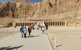 Hatshepsut Temple in Luxor with tourists walking towards the ancient structure.
