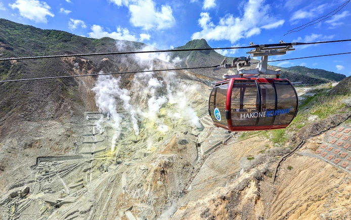 Hakone Ropeway cable car over Owakudani volcanic valley with steam vents, Japan.