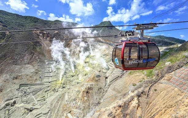 Hakone Ropeway cable car over Owakudani volcanic valley with steam vents, Japan.