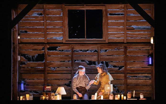 Two people in a dimly lit cabin with candles, one blindfolded, evoking a Stranger Things theme.