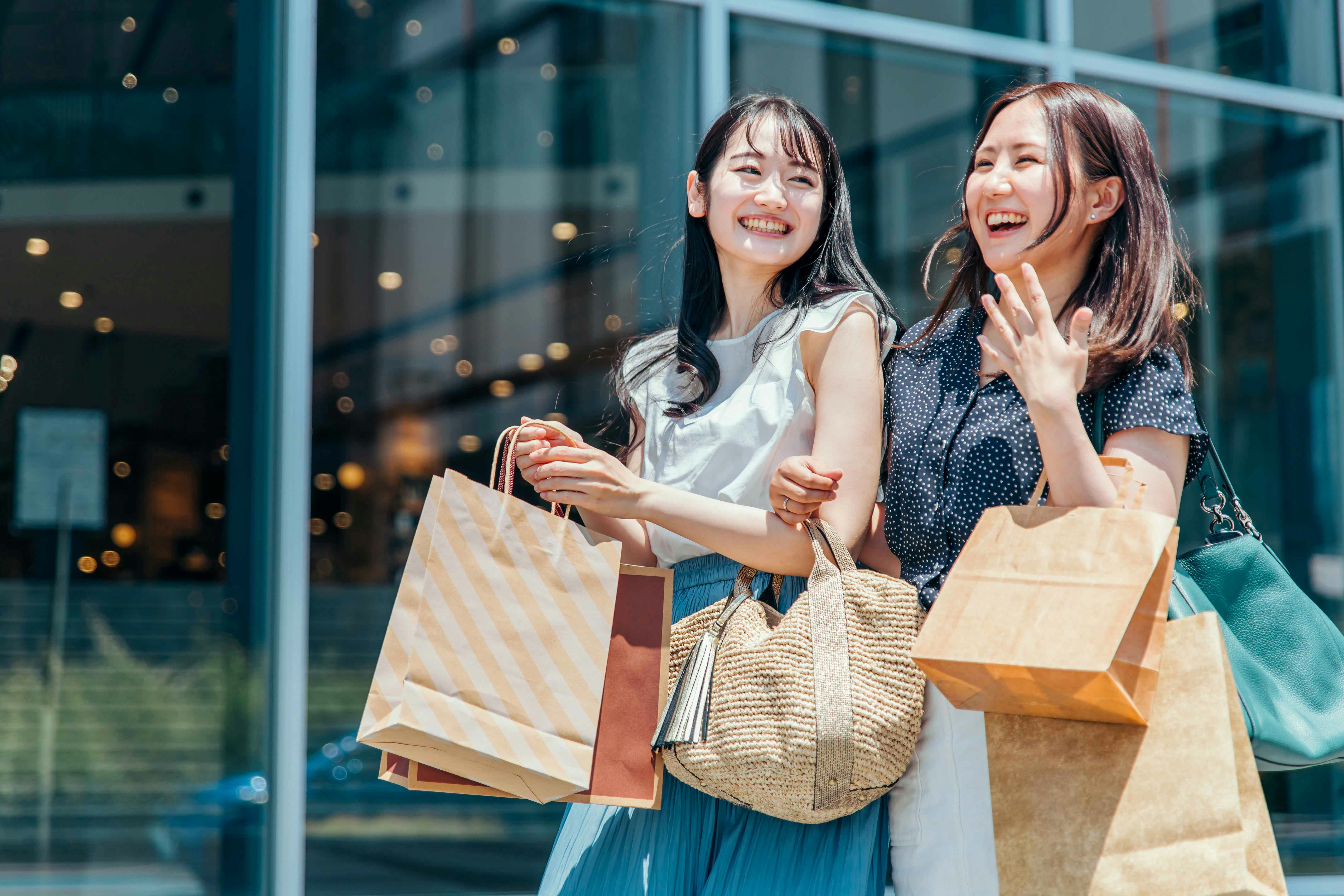 Two people smiling and holding shopping bags outside S.E.A Aquarium Singapore.