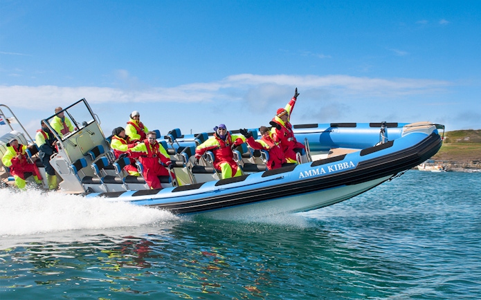 RIB speedboat with passengers on Husavik waters during whale and puffin tour, Iceland.