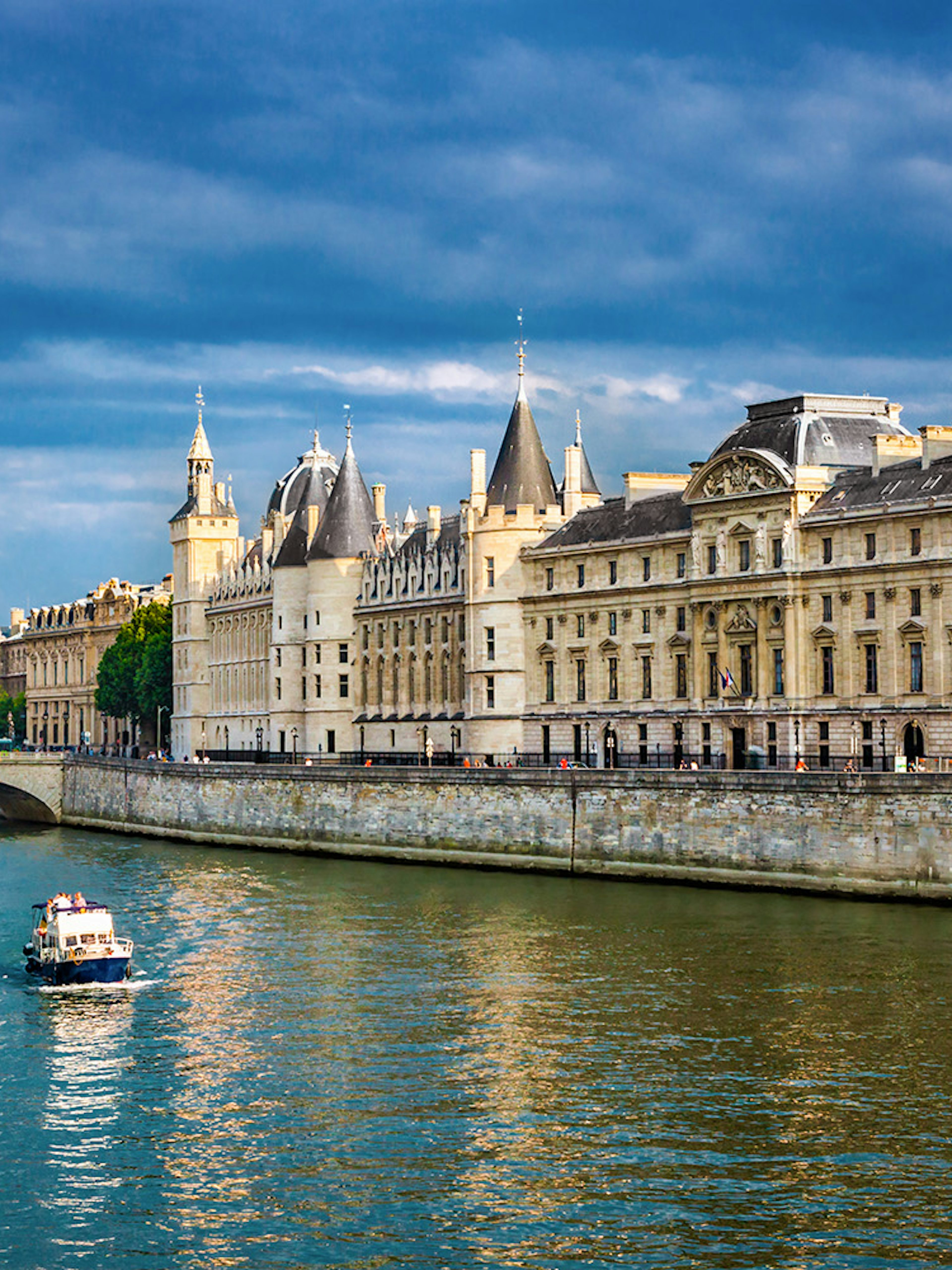 Conciergerie in Paris with boats on the Seine River.