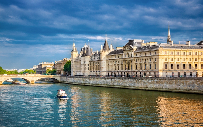 Conciergerie in Paris with boats on the Seine River.