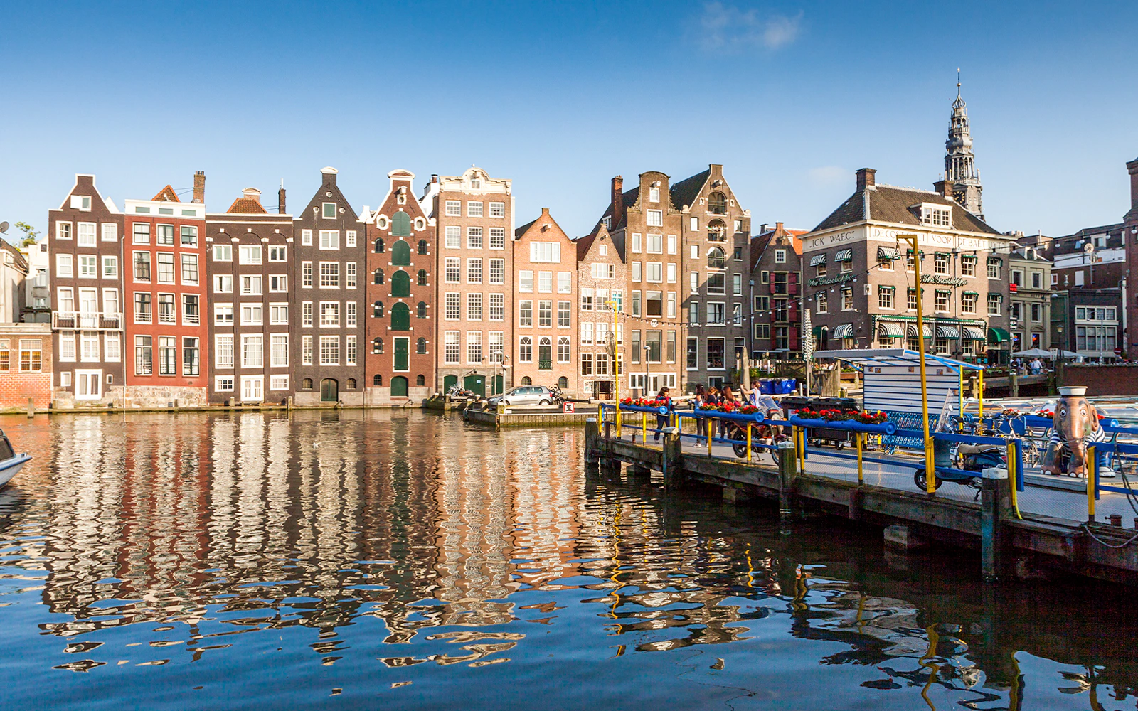 Canal houses along Amsterdam's waterfront with a boat docked nearby.
