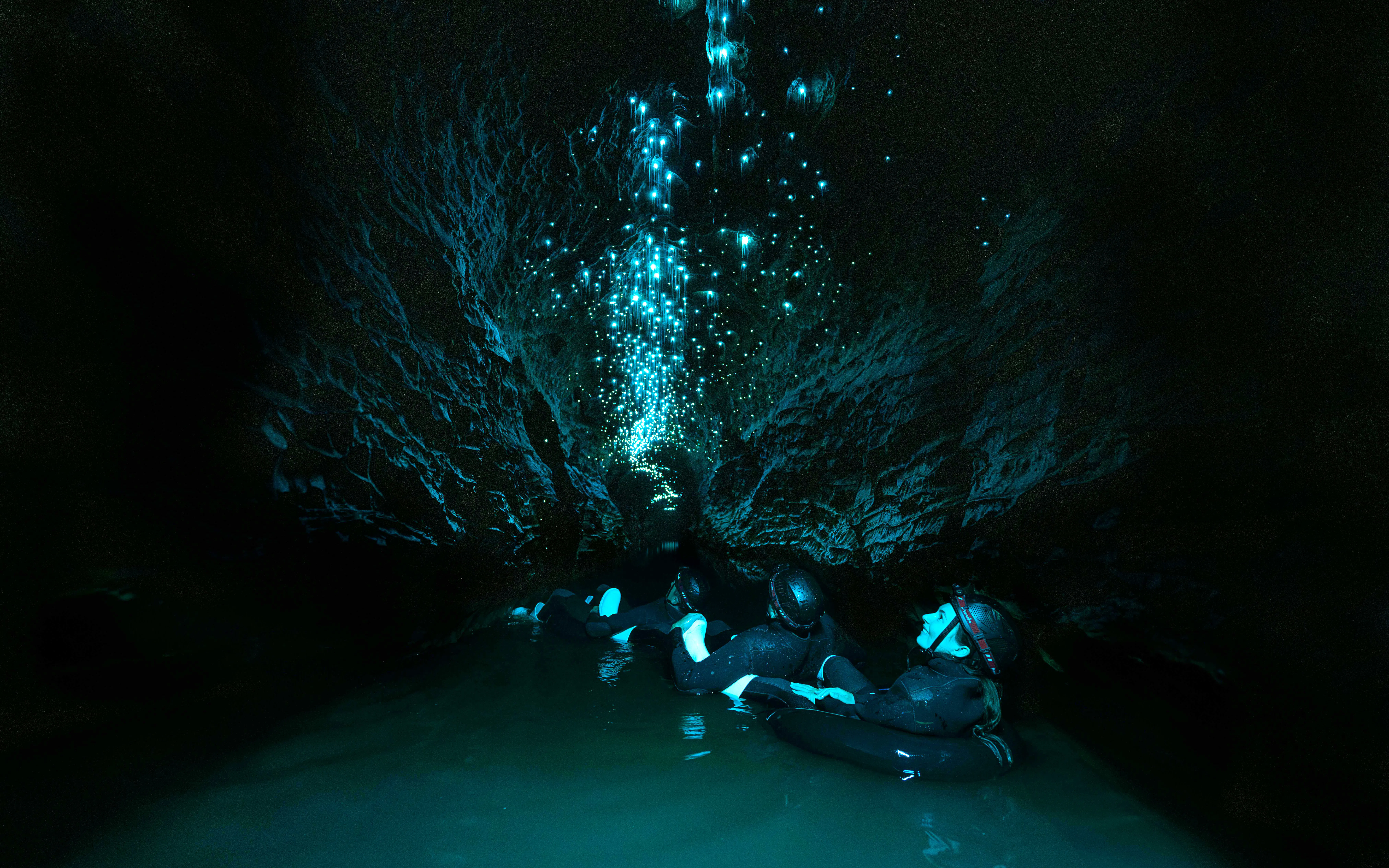 Visitors floating in Okohua Glowworm Cave, illuminated by glowworms, Waitomo Experience.