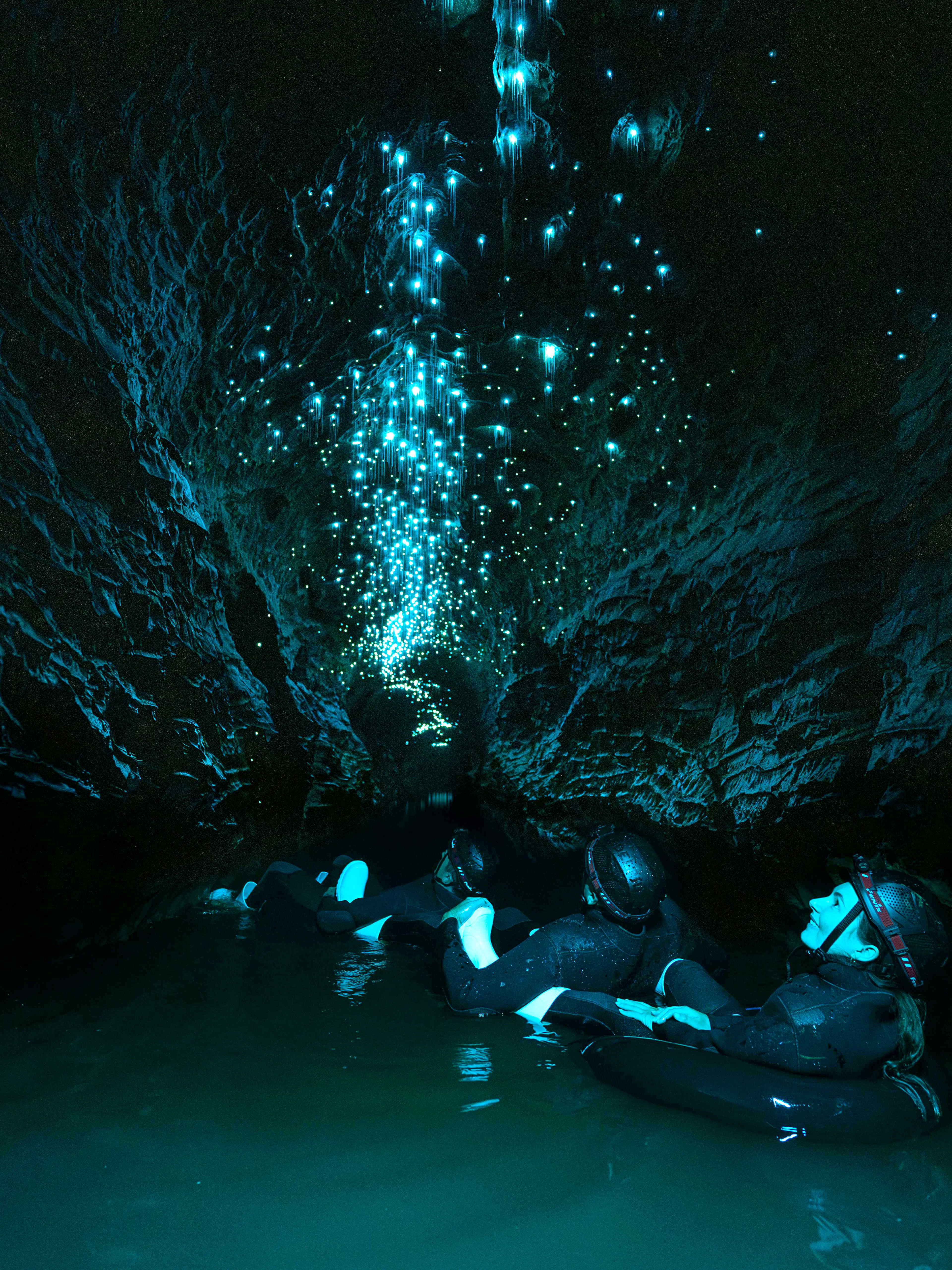 Visitors floating in Okohua Glowworm Cave, illuminated by glowworms, Waitomo Experience.
