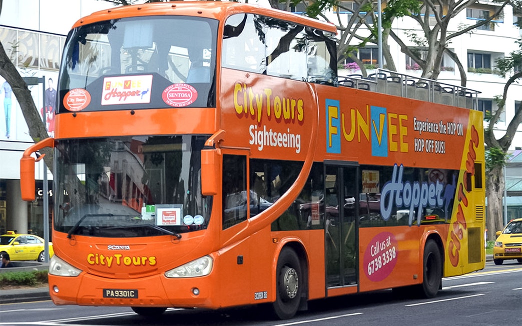 Open-top orange FunVee bus on Singapore city tour route.
