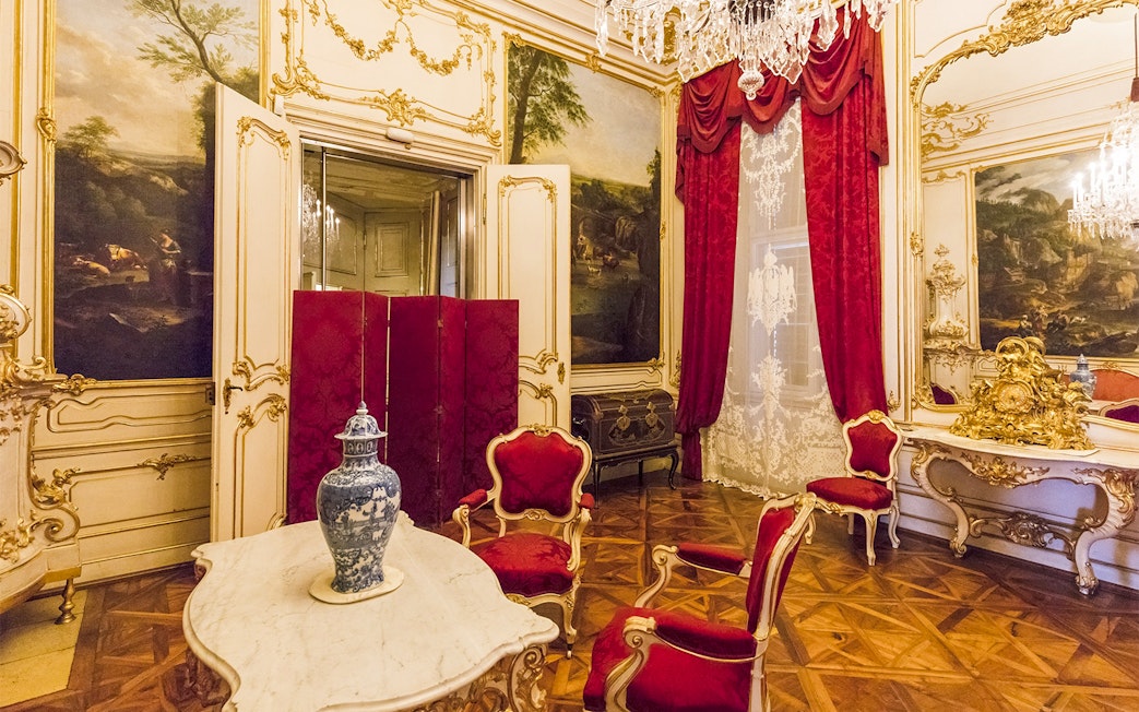 Elegant room in Schönbrunn Palace, Vienna, featuring ornate decor and red velvet chairs.