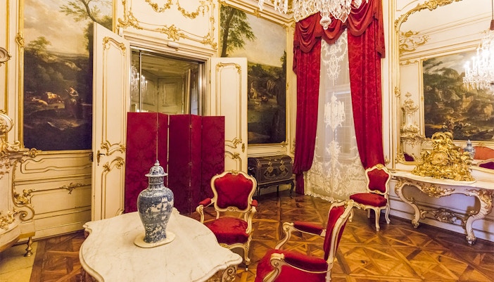 Elegant room in Schönbrunn Palace, Vienna, featuring ornate decor and red velvet chairs.