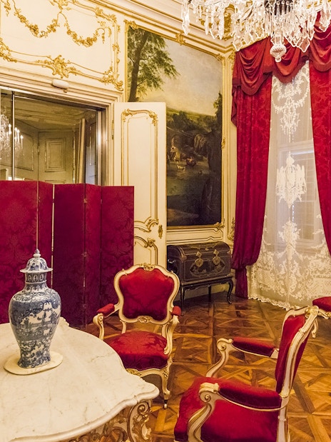 Elegant room in Schönbrunn Palace, Vienna, featuring ornate decor and red velvet chairs.