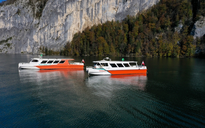 Cruise boats on Wolfgang's Lake with rocky cliffs and forest backdrop.