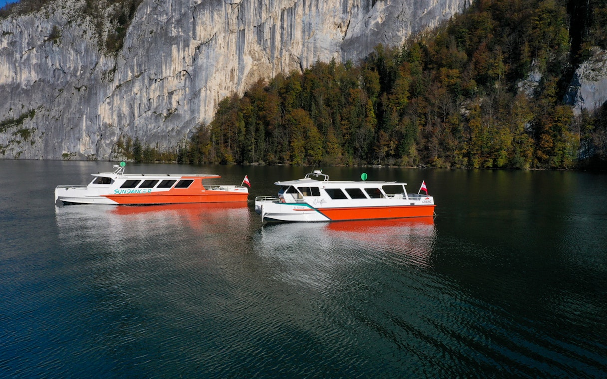 Cruise boats on Wolfgang's Lake with rocky cliffs and forest backdrop.