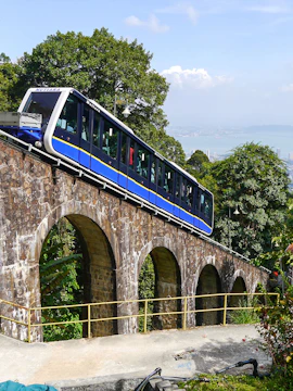 Funicular train ascending Penang Hill, Malaysia, with scenic views and lush greenery.