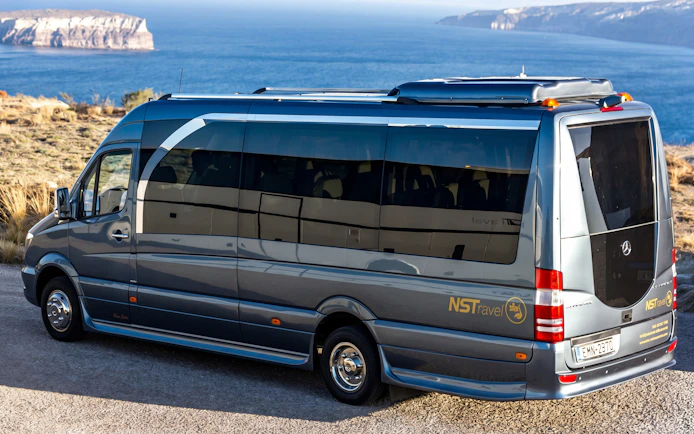 Tour bus overlooking Santorini coastline during sunset wine tour.