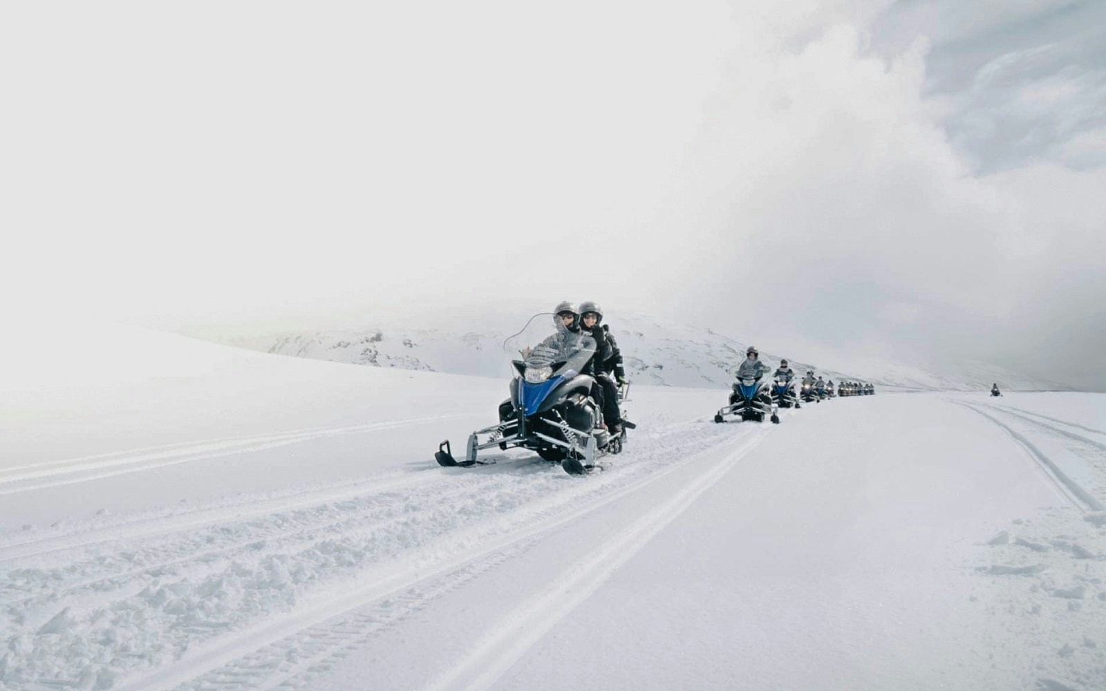 Guests riding snowmobiles on a snowy trail from Gullfoss waterfall in Iceland.