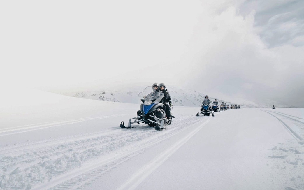 Guests riding snowmobiles on a snowy trail from Gullfoss waterfall in Iceland.