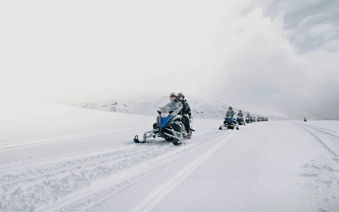 Guests riding snowmobiles on a snowy trail from Gullfoss waterfall in Iceland.