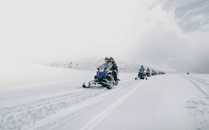 Guests riding snowmobiles on a snowy trail from Gullfoss waterfall in Iceland.