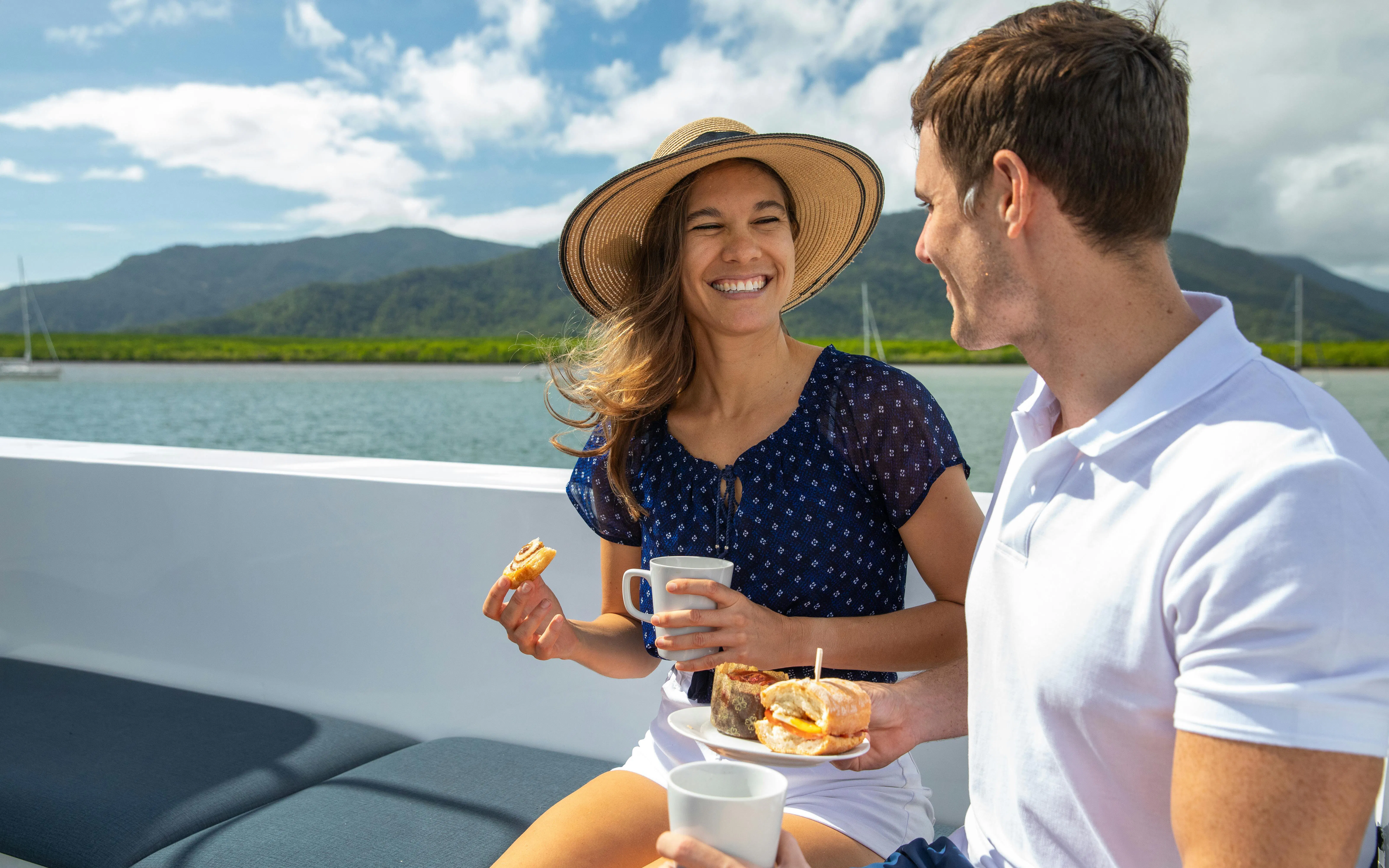 Couple enjoying snacks on a boat during a Cairns snorkelling tour, Great Barrier Reef.