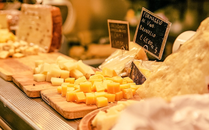 Cheese selection on wooden boards in a store with price tags.