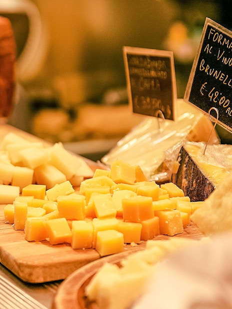 Cheese selection on wooden boards in a store with price tags.