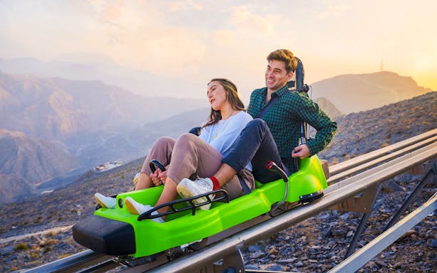 Couple enjoying the Jais Sledder ride in Ras Al Khaimah with mountain views.