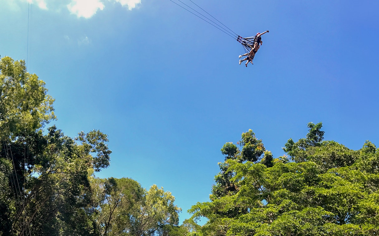 Participants swinging on the Cairns Giant Swing against a clear blue sky.